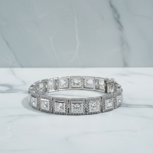 Diamond bracelet on a white surface with green foliage in the background