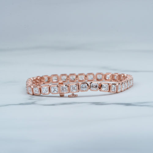 Rose gold bracelet with diamonds on a light surface with greenery in the background