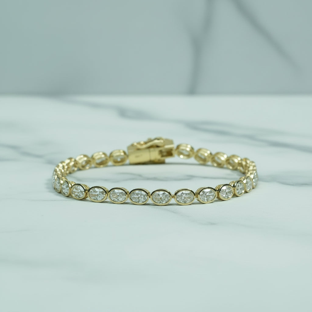 Gold bracelet with clear stones on a light surface with green foliage in the background