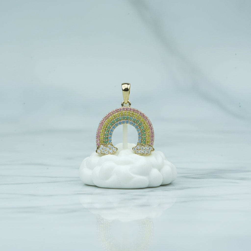 Gold rainbow-shaped pendant on a white background with greenery and flowers.