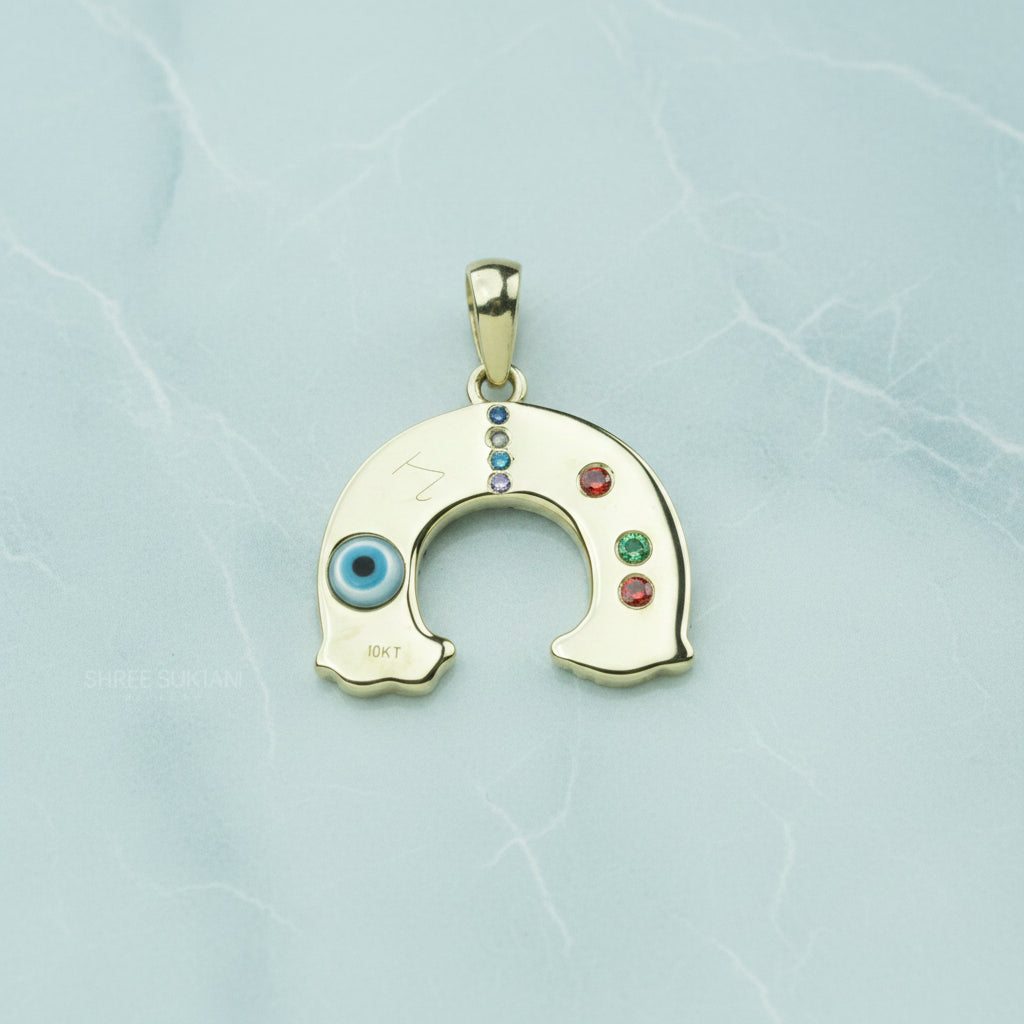 Gold pendant with colored stones on a white surface with a floral background