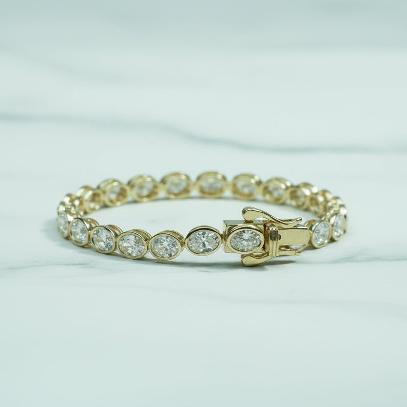 Gold bracelet with clear stones on a light background with blurred greenery
